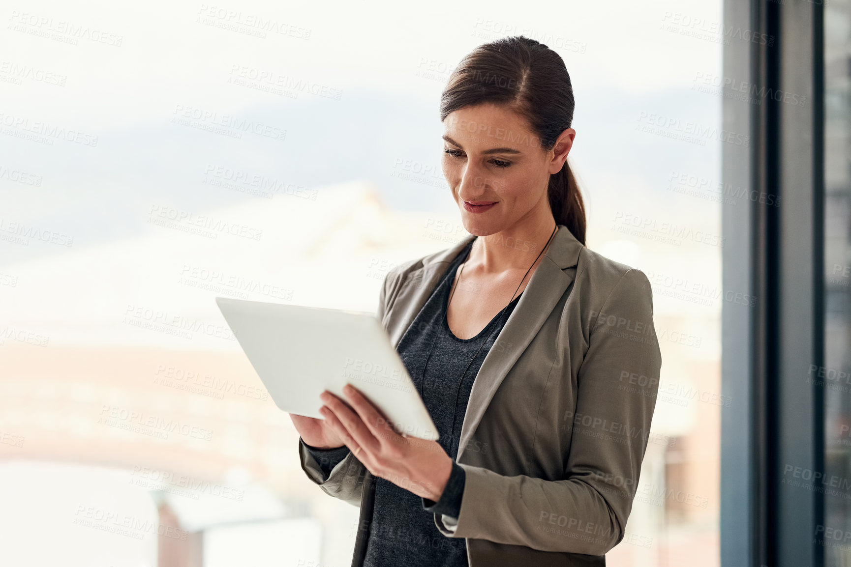 Buy stock photo Cropped shot of a young businesswoman working on a digital tablet in an office