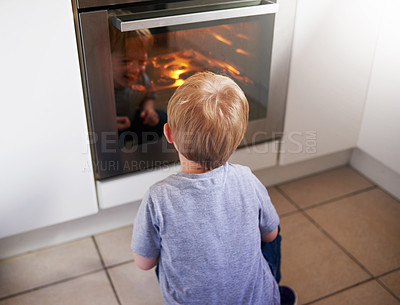 Buy stock photo Rear view shot of a little boy looking at some cake baking in an over