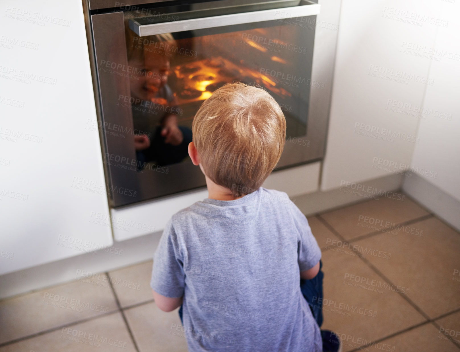 Buy stock photo Rear view shot of a little boy looking at some cake baking in an over