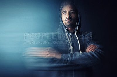 Buy stock photo Studio shot of a young man standing with his arms folded against a dark background