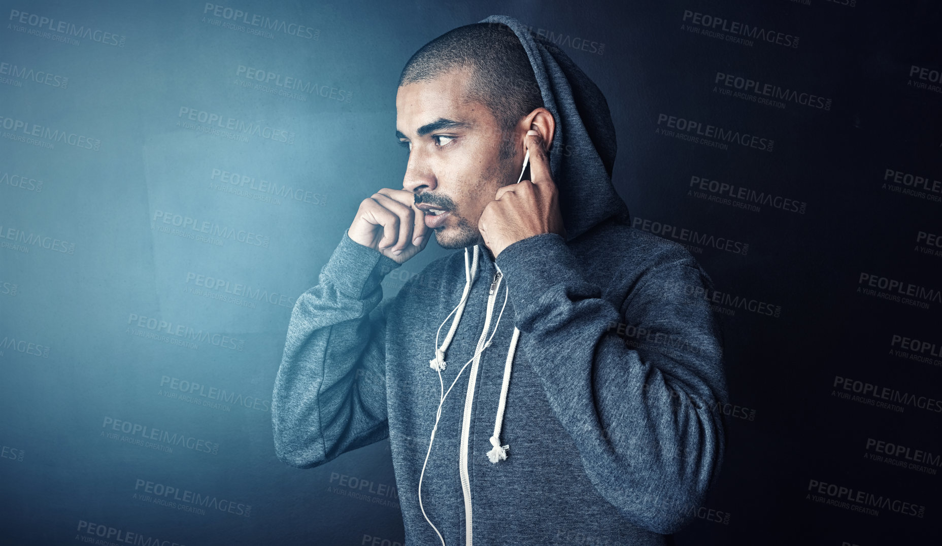 Buy stock photo Gym, listening and man in studio with earphones, hoodie and mockup space for health workout. Thinking, streaming and athlete on music app for exercise, inspiration and playlist on dark background