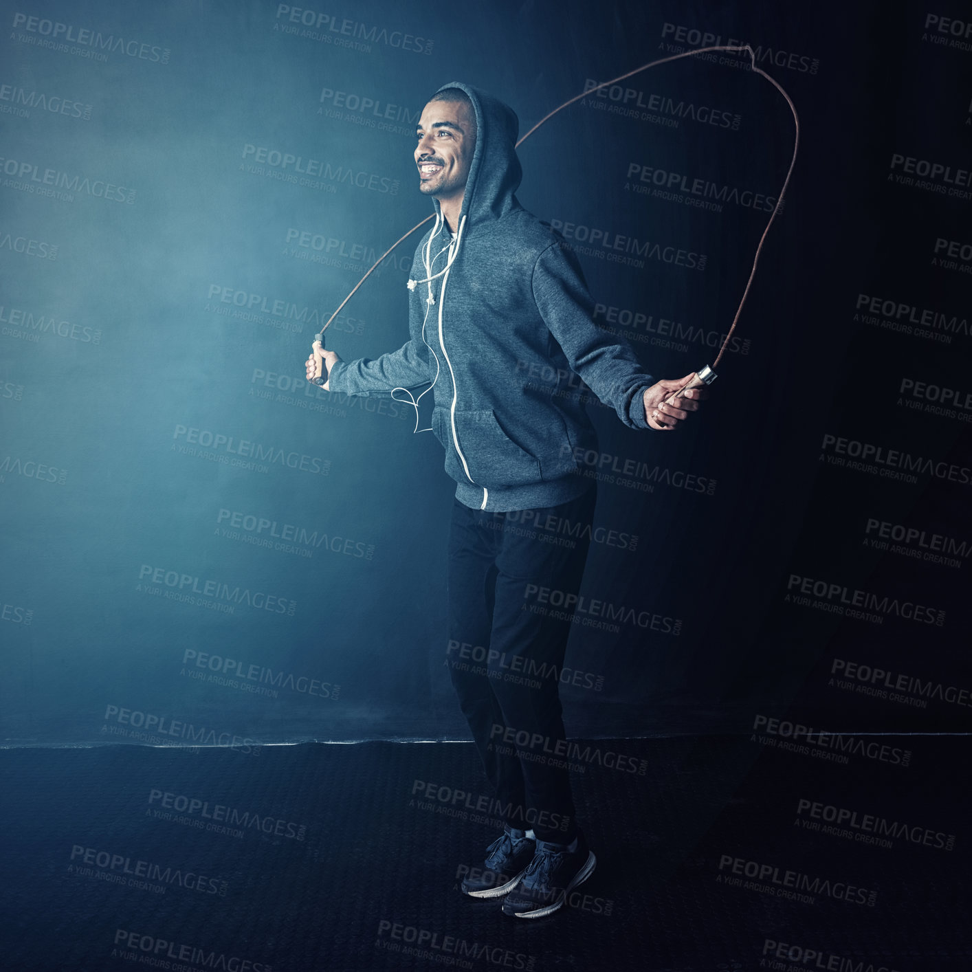 Buy stock photo Man, jumping rope and fitness with smile from cardio and impact training for boxing in gym studio. Exercise, African athlete and health with wellness, workout and skip for sport and dark background