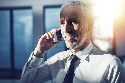 Buy stock photo Shot of a businessman standing in an office talking on a cellphone