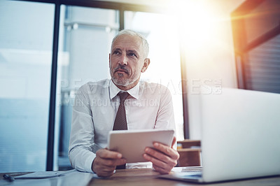 Buy stock photo Shot of a businessman sitting at his desk using a digital tablet