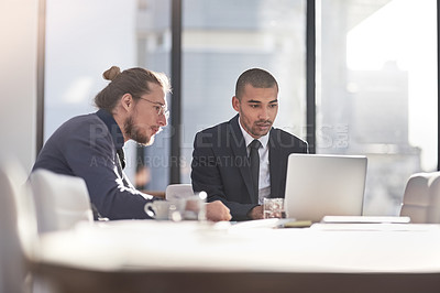 Buy stock photo Shot of two young businessmen using a laptop together at work