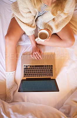Buy stock photo Shot of an unidentifiable woman using her laptop while enjoying a cup of coffee in bed