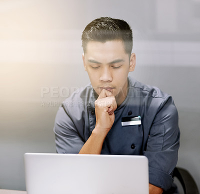 Buy stock photo Cropped shot of a thoughtful young man working on his laptop