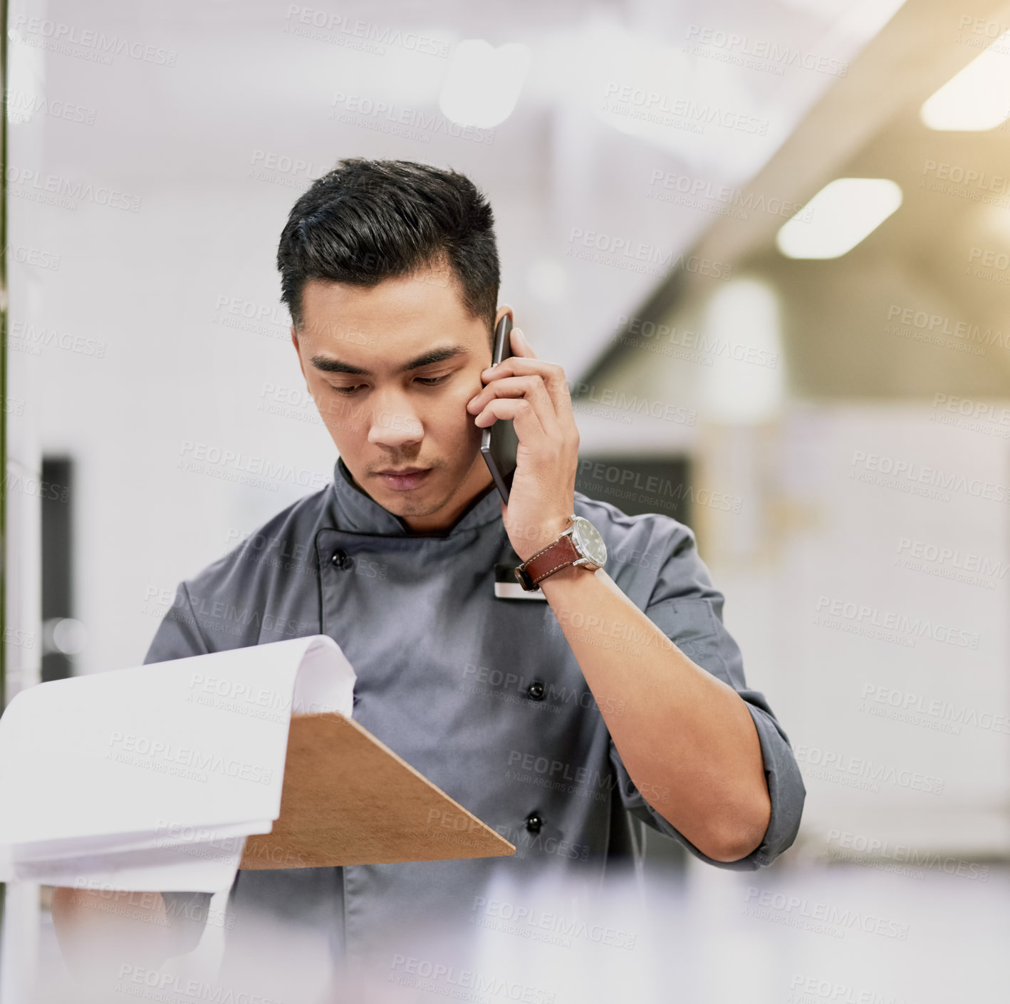 Buy stock photo Cropped shot of a young male reading a customer's order while talking on his cellphone