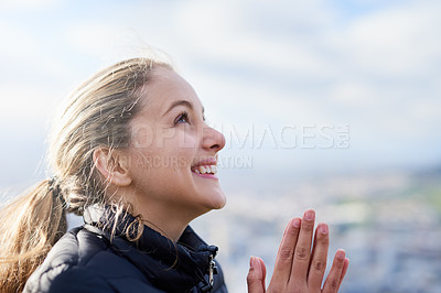 Buy stock photo Cropped shot of an attractive young woman standing with her hands together in prayer outside