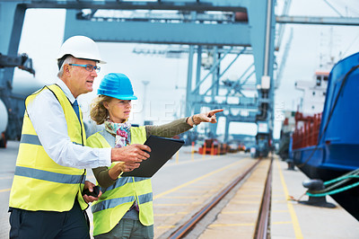 Buy stock photo Two dock workers conferring among themselves while surveying the harbor