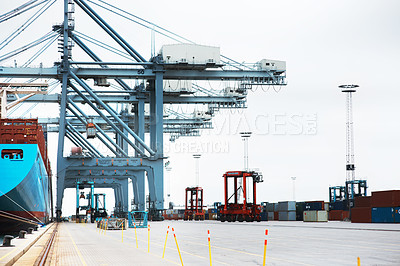 Buy stock photo A massive cargo ship moored at the harbor while being loaded with containers