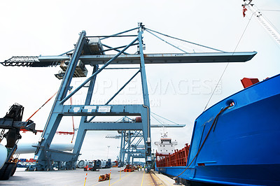 Buy stock photo Rail mounted gantry loading and unloading container at the port. A massive cargo ship moored at the harbor while being loaded with containers. A cargo bulk carrier being loaded at the dockyard.