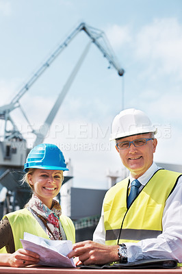 Buy stock photo Two dock workers holding paperwork while standing in the shipyard