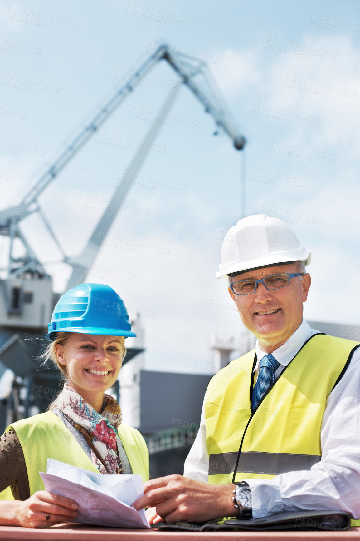 Buy stock photo Two dock workers holding paperwork while standing in the shipyard