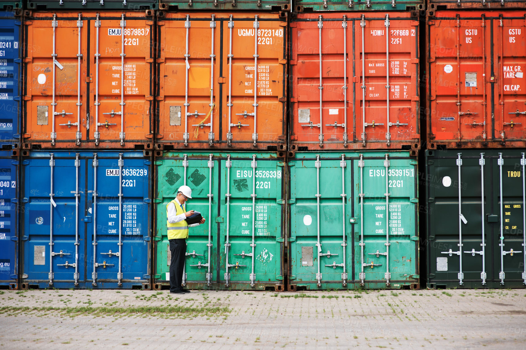 Buy stock photo A customs inspector standing and reviewing a tack of containers