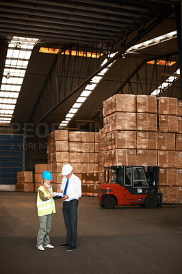 Buy stock photo Two colleagues talking to one another in a warehouse.