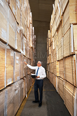 Buy stock photo A manager standing in an aisle in a warehouse examining the cardboard containers