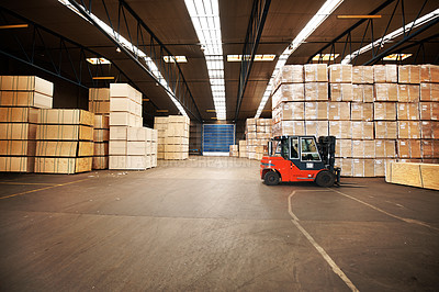 Buy stock photo A large warehouse storing big boxes with a forklift.