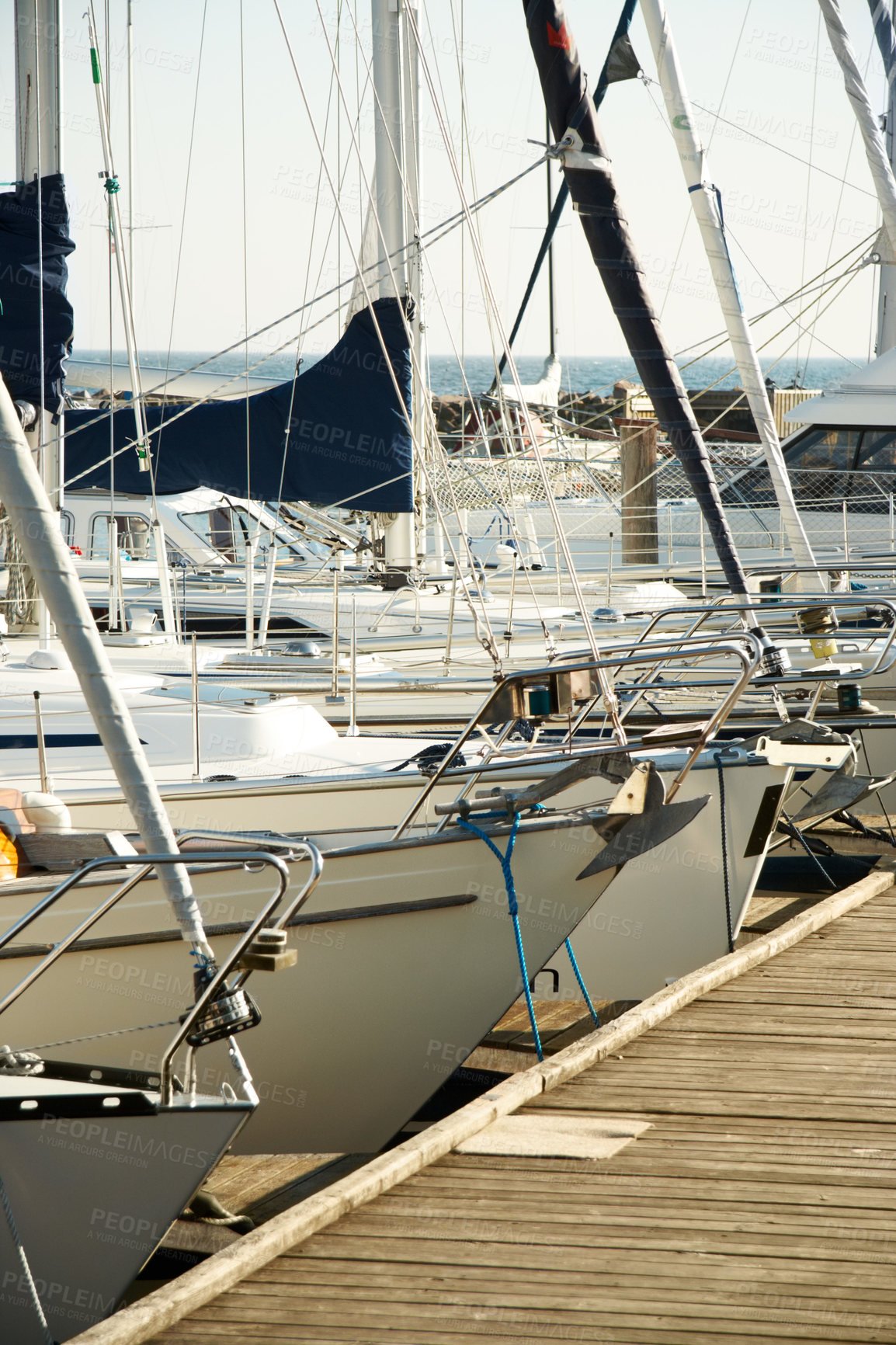 Buy stock photo A row of many yachts and boats at a harbour by the sea. Lots of anchored luxury sailboats and ships at a pier ready to be used for travel, leisure, fishing, water sports or a scenic trip at quayside