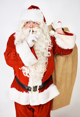 Buy stock photo Santa claus, quiet and secret for present in studio for Christmas giving, festive season joy or fun. Male person, surprise emoji and sack or costume on white background, holiday or vacation break