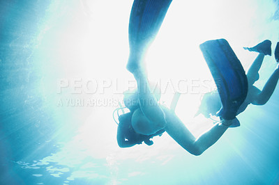 Buy stock photo Bottom view of two scuba divers as they ascend to the sunny surface - Copyspace