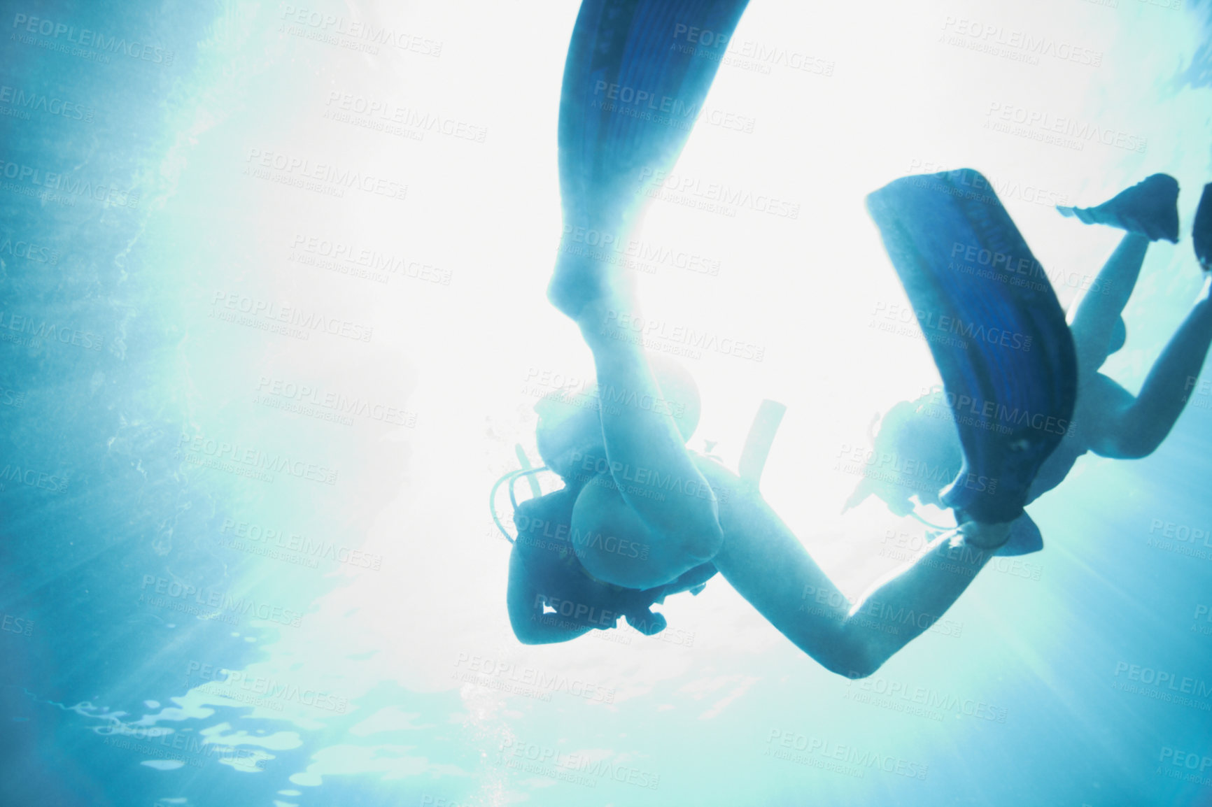 Buy stock photo Bottom view of two scuba divers as they ascend to the sunny surface - Copyspace