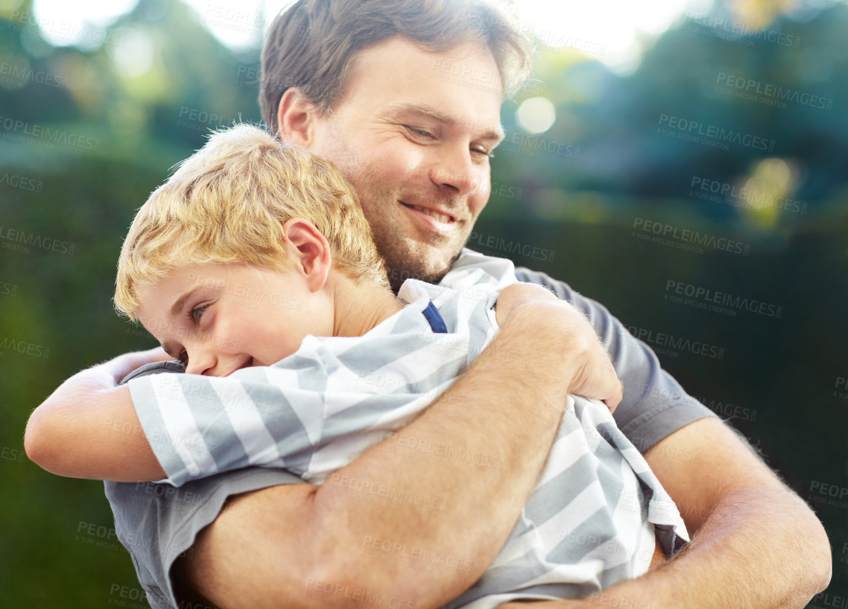 Buy stock photo Shot of a smiling father hugging his son outside