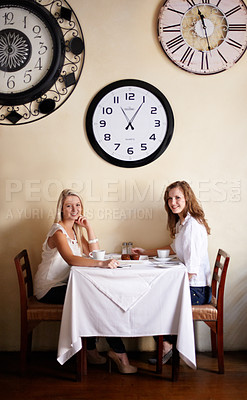 Buy stock photo Two smiling young woman enjoying tea while in a coffee shop - portrait