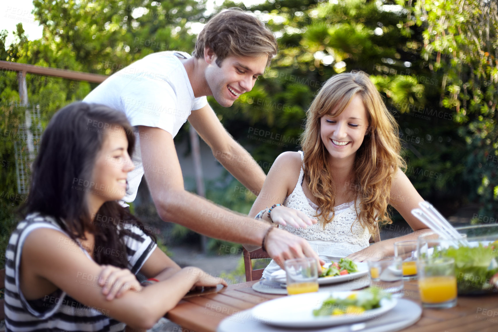 Buy stock photo Happy, friends and food serve in backyard with salad at a table with hungry people and smile. Lunch, home garden and group ready for eating with healthy meal together and relax outdoor and laughing