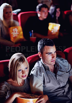 Buy stock photo Cinema, date and couple with popcorn, watching film or eating on romantic night together. Movie, man and woman in theater with snacks, show and sitting in auditorium to relax in evening with partner.