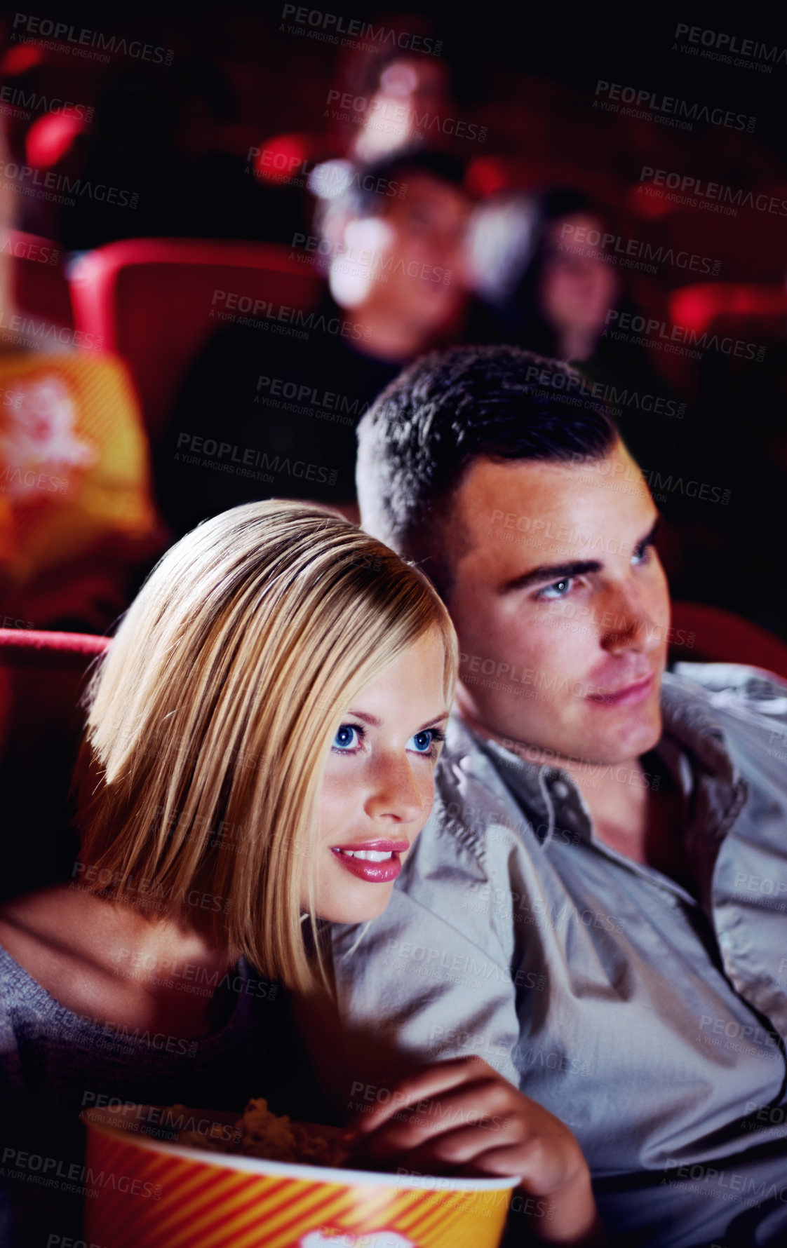 Buy stock photo A cute young couple watching a scary movie in a cinema together