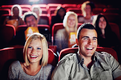 Buy stock photo A couple laughing and watching a movie together at the cinema