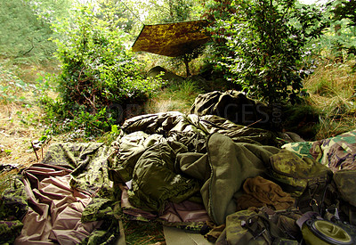 Buy stock photo Empty infantry soldier campsite hiding under camouflage in green forest. Camo camp tents, sleeping bags and army equipment in the middle of the woods during the day. No people in battlefield shelter