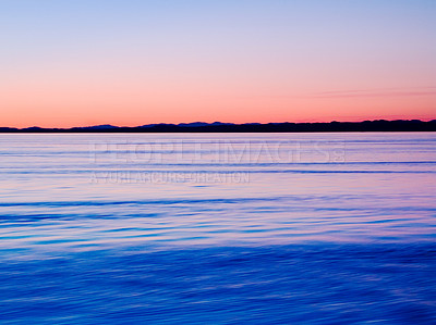 Buy stock photo A calm lake and a gorgeous sunset with a serene view at the sunset. Relaxing seascape with a vast horizon of the sky and the sea with copyspace. Skyscape of dawn with gradient sky at a seaside