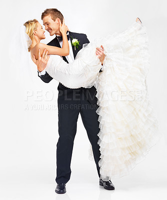 Buy stock photo Happy, wedding and young couple after a marriage event with love, commitment and happiness. Man lifting bride with a smile, suit and rose ready to kiss and start life with a studio white background 