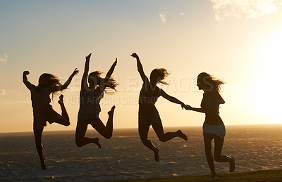 Buy stock photo Silhouette of a group of girlfriends on the beach having lots of fun jumping around