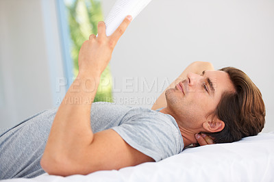 Buy stock photo Man, bedroom and reading books in home for story, interesting novel and learning knowledge. Guy relax with notebook of fiction for break, studying literature or hobby to enjoy in comfort in apartment
