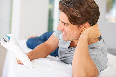 Buy stock photo Man, bedroom and reading books with smile for story, novel or study knowledge in comfort at home. Happy guy relax with notebook of fiction for rest, studying literature or hobby to enjoy in apartment