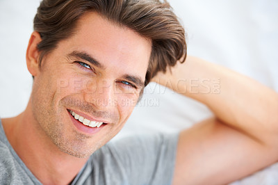 Buy stock photo Portrait of a handsome young man lying in bed and leaning on his hands
