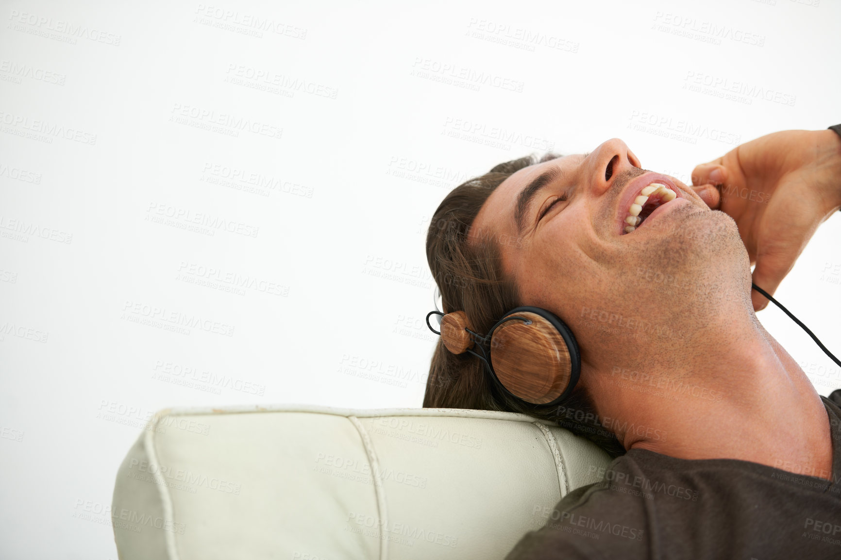 Buy stock photo Headphones, happy and young man relaxing on chair in studio listening to music, radio or playlist. Smile, technology and male person streaming song or album and chilling isolated by white background.