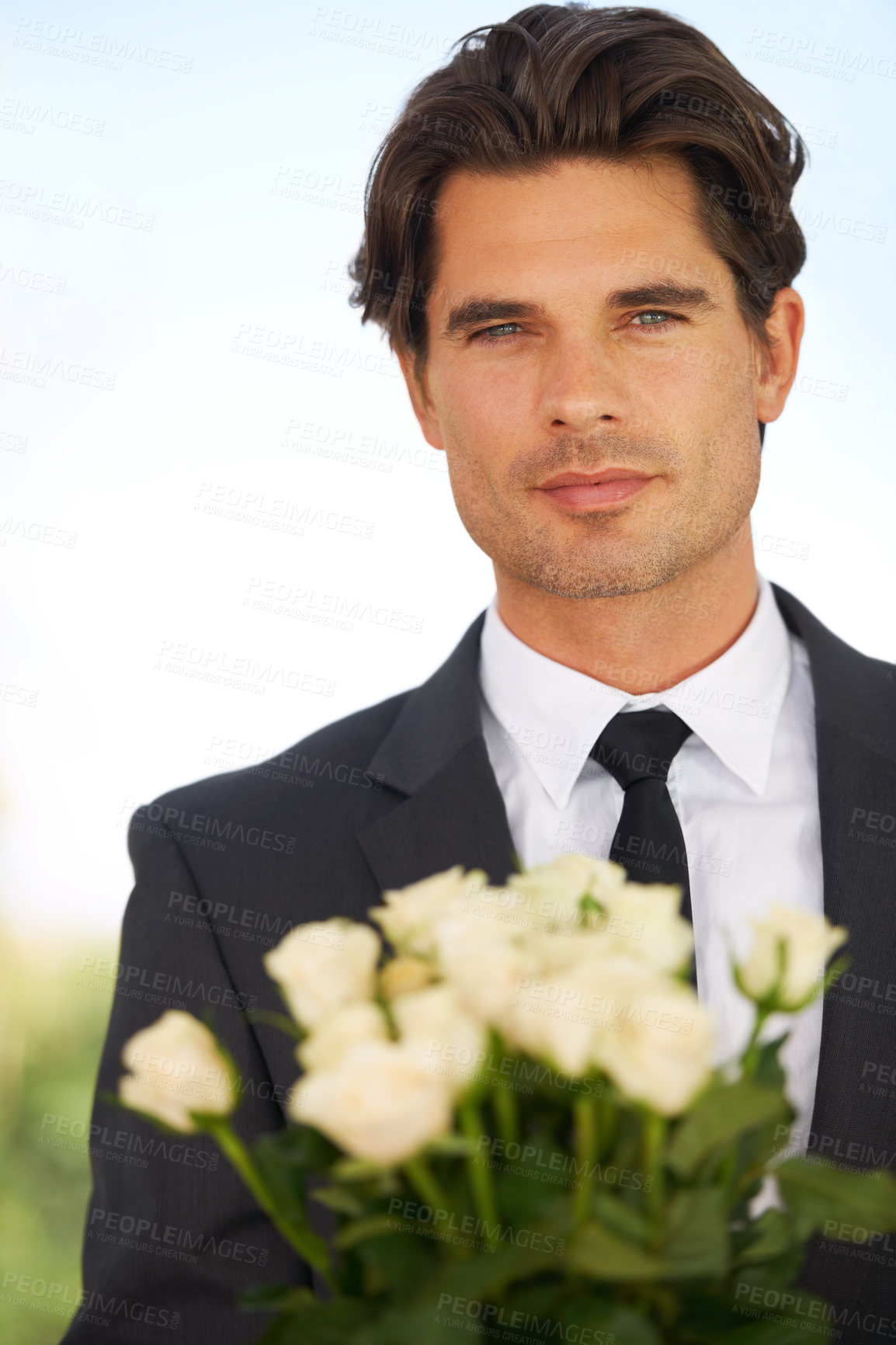 Buy stock photo Portrait of a handsome young man wearing a suit and holding a bunch of roses