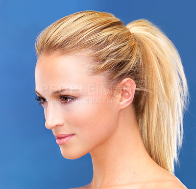 Buy stock photo Face, beauty and hair of a woman closeup in studio on a blue background for skin wellness or cosmetics. Aesthetic, skincare and ponytail with a young model profile at the salon for dermatology