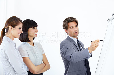 Buy stock photo Three young and ambitious executives strategizing together on a whiteboard