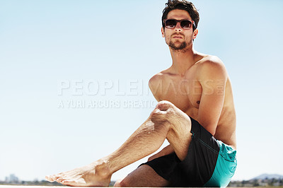Buy stock photo A handsome young male wearing sunglasses while relaxing on a sunny summer day - Copyspace