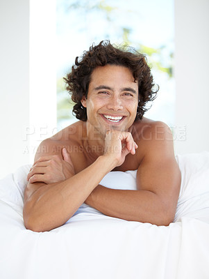 Buy stock photo Portrait, smile and bedroom with a man lying on a bed in his home to relax or rest on a summer morning. Happy, wellness and lifestyle with an attractive young male person relaxing alone in his house