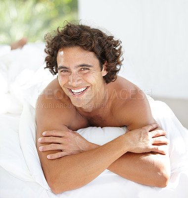 Buy stock photo Portrait, happy and relax with a man on a bed in his home, lying in the bedroom to rest on a summer morning. Smile, wellness and lifestyle with an attractive young male person relaxing in his house