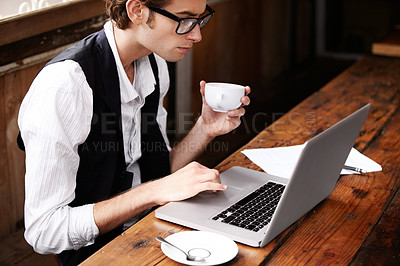 Buy stock photo Shot of a young man sitting in a cafe working on a laptop