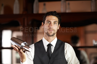 Buy stock photo Portrait of a handsome young bartender mixing a cocktail for a customer