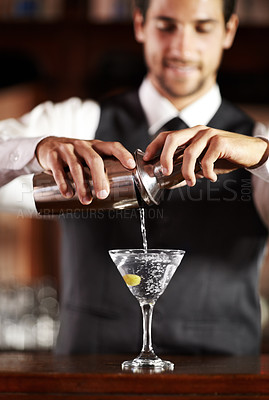 Buy stock photo Shot of a handsome young bartender mixing a cocktail