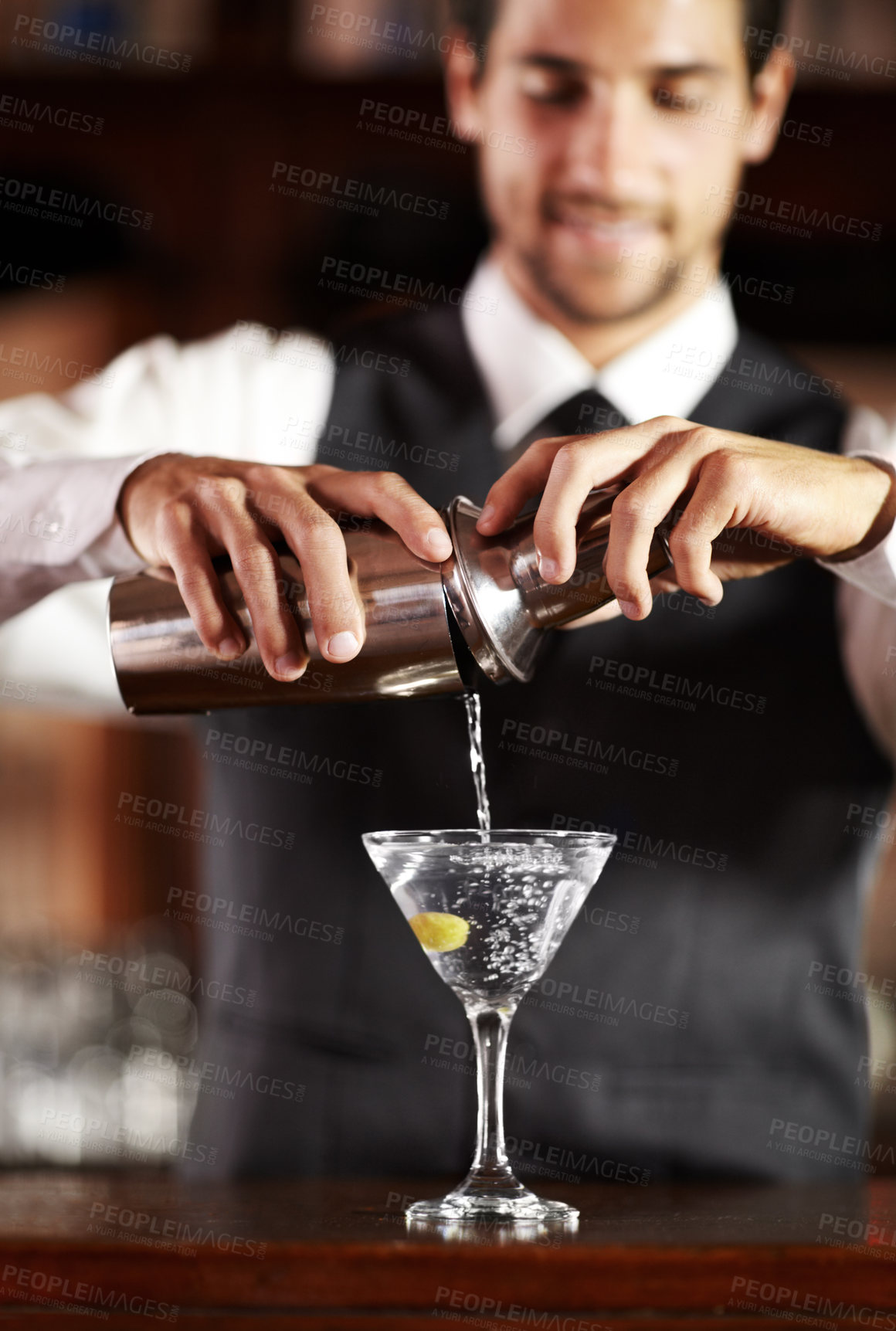 Buy stock photo Shot of a handsome young bartender mixing a cocktail